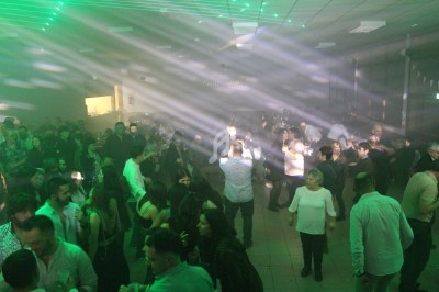 Salle comble avec des personnes dansant sous des jeux de lumière colorés lors d'une soirée festive.