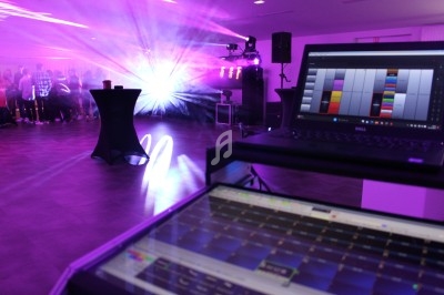 Ordinateur portable affichant un logiciel de contrôle lumineux dans une salle avec éclairage coloré et des personnes en…