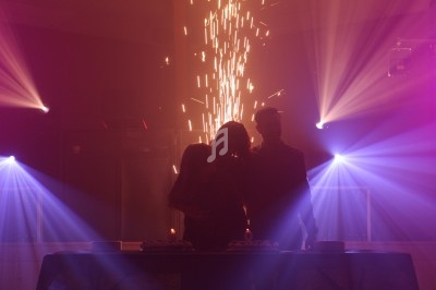 Une famille devant une table éclairée par des projecteurs et des étincelles dans une ambiance festive sombre.