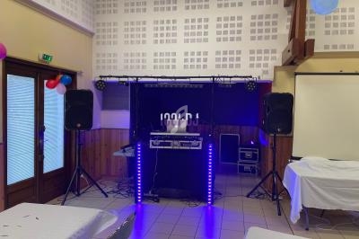 Installation de matériel de sonorisation et éclairage dans une salle avec tables décorées et projecteur.