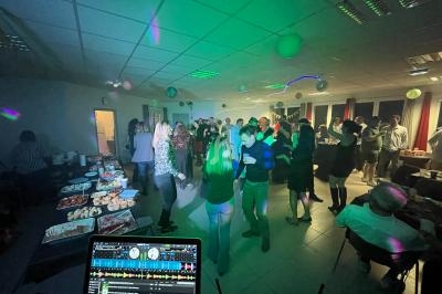 Groupe de personnes dans une salle éclairée par des lumières colorées, dansant et socialisant près d'une table de buffet.