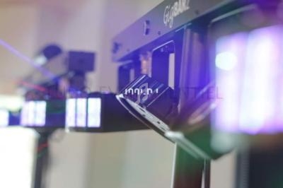 Projecteurs lumineux alignés, émettant des faisceaux colorés dans un environnement intérieur flou.