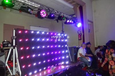 Mur lumineux à LED multicolores dans une salle, avec des personnes assises sur le côté et des équipements techniques…