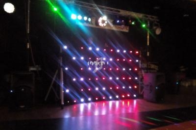 Mur lumineux à LED colorées installé dans une salle sombre, avec des projecteurs et des équipements audio visibles.