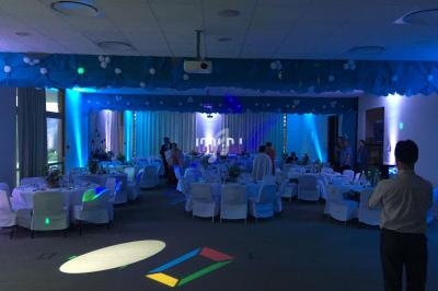 Salle de réception décorée avec des tables dressées, éclairage tamisé et ambiance festive.