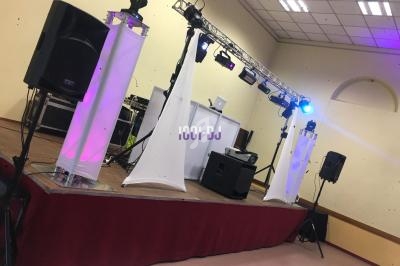 Installation de matériel de sonorisation et d'éclairage sur une scène dans une salle intérieure.