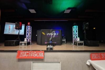 Scène de spectacle avec des équipements audio et lumineux, affiches ’High School’ en bas de l'estrade.