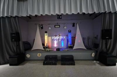 Scène de spectacle avec éclairage coloré, rideaux gris, enceintes, et décorations minimalistes.