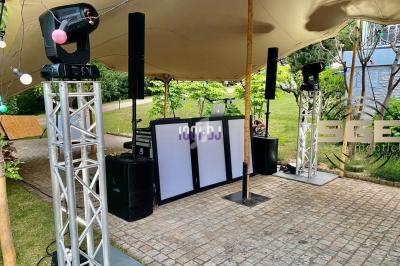 Installation de matériel de sonorisation et d'éclairage sous une tente en extérieur, avec une piste pavée.