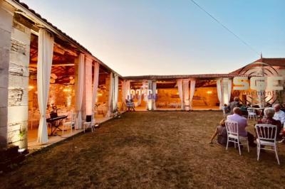 Cour intérieure d'une bâtisse en pierre, aménagée pour un événement avec éclairages et tables dressées.