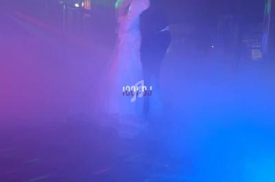 Un couple danse dans une ambiance lumineuse colorée et enveloppée de fumée.