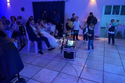 Des enfants jouent devant des invités assis dans une salle éclairée de lumières bleues lors d'une réception.
