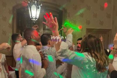 Personnes dansant sous des lumières colorées dans une salle décorée avec des murs ornés et un lustre suspendu.