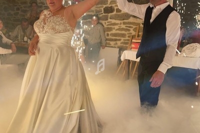Un couple danse lors d'une fête, entouré de fumée au sol et d'étincelles dans une salle en pierre.