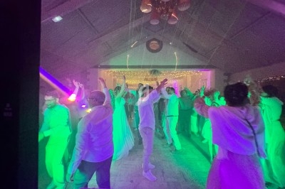 Personnes dansant sous des lumières colorées dans une salle décorée avec des guirlandes lumineuses.