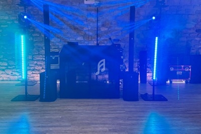 Installation de matériel de sonorisation et d'éclairage avec effets lumineux bleus dans une salle en pierre.