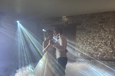 Un couple danse dans une ambiance romantique avec des faisceaux lumineux et de la fumée dans une salle en pierre.