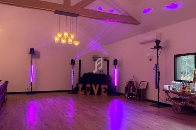 Salle de réception avec éclairage violet, piste de danse, lettres lumineuses ’LOVE’ et équipements audio.