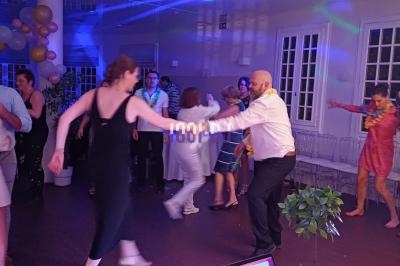Des personnes dansent dans une salle éclairée avec des lumières colorées, entourées de décorations festives.