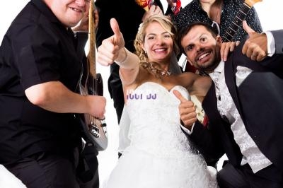 Un groupe de musiciens pose joyeusement avec une mariée et un marié en tenue de mariage.