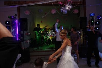 Une mariée danse avec une enfant devant un groupe de musique jouant lors d'une réception festive.
