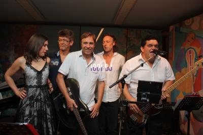 Un groupe de musiciens sur scène avec des instruments, dont une guitare et une basse, dans un cadre intérieur.