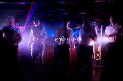 Des personnes dansent dans une ambiance de boîte de nuit avec des lumières colorées et des effets laser.