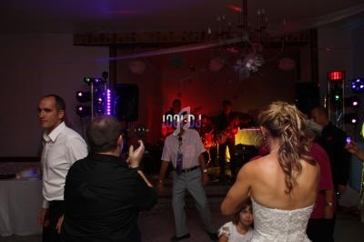 Des invités dansent devant un groupe de musique lors d'une réception de mariage dans une salle décorée.
