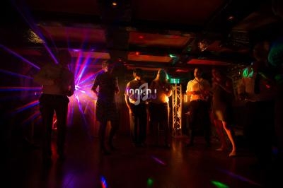 Des personnes dansent dans une salle sombre éclairée par des lumières colorées et des effets lumineux.