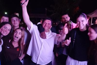 Groupe de personnes souriantes posant ensemble lors d'un événement en soirée, sous des lumières colorées.