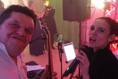 Un homme et une femme chantent et jouent de la musique lors d'un événement festif en intérieur.