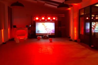 Salle éclairée en rouge avec un écran de projection, des lumières et des équipements audio-visuels.
