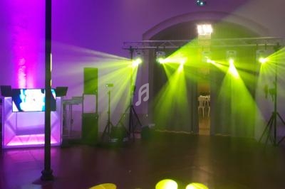 Salle de réception avec éclairage coloré, projecteurs jaunes et équipement audio-visuel installé.