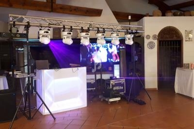 Installation de matériel de sonorisation et d'éclairage avec écran et projecteurs dans une salle au sol carrelé.