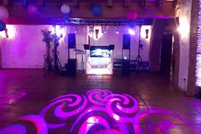 Salle de réception avec éclairage coloré, piste de danse illuminée et équipement de sonorisation installé.