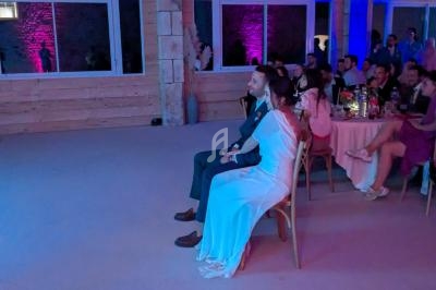 Un couple assis dans une salle éclairée de lumières colorées, entouré d'invités lors d'un événement festif.