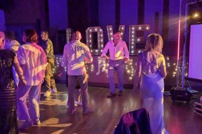 Des personnes dansent dans une salle faiblement éclairée, décorée de lumières et d'un panneau lumineux ’LOVE’.