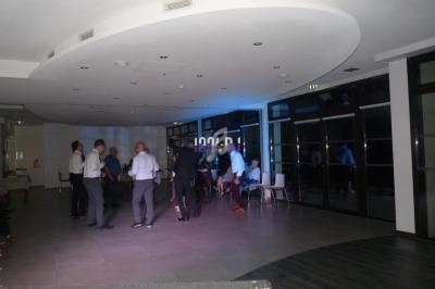 Des personnes debout et assises discutent dans une salle spacieuse avec un éclairage tamisé.