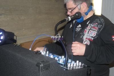 Un homme utilise une table de mixage avec un micro et un casque audio dans un environnement intérieur.