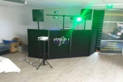 Équipement de sonorisation et éclairage installé dans une salle, avec une table et des éléments de rangement en arrière-plan.