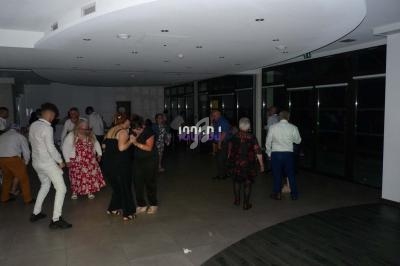 Des personnes dansent dans une salle sombre avec un éclairage tamisé et de grandes baies vitrées.