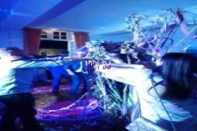 Des personnes dansent sous des lumières colorées, entourées de décorations festives et de confettis.