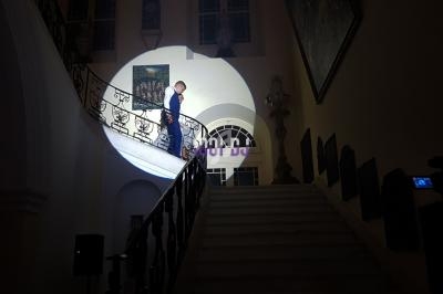 Un homme descend un escalier éclairé par un projecteur dans un intérieur sombre et élégant.