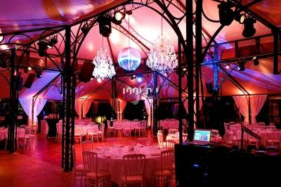 Salle de réception décorée avec des lustres, éclairage coloré et tables dressées pour un événement.