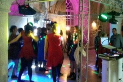 Des personnes dansent sous des jeux de lumière colorés dans une salle avec des voûtes en pierre.