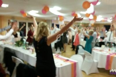 Des personnes debout dans une salle décorée, bras levés, participant à une animation lors d'un événement festif.