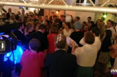 Groupe de personnes rassemblées dans une salle, certaines dansant ou discutant sous un éclairage festif.