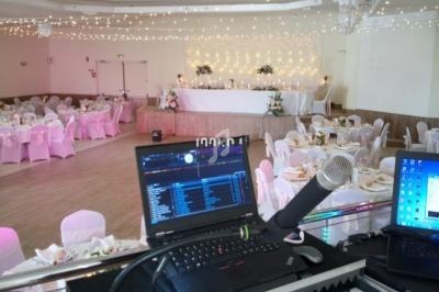 Vue depuis une table de mixage dans une salle de réception décorée pour un mariage avec des guirlandes lumineuses.