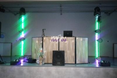 Installation de matériel de sonorisation et éclairage coloré sur une scène avec une table de mixage au centre.