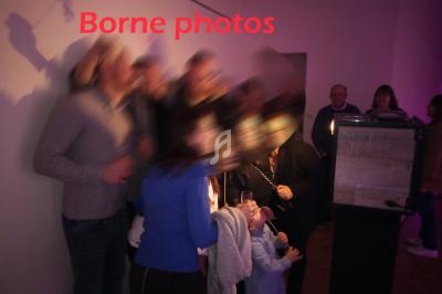 Un groupe de personnes posant près d'une borne photo dans une pièce éclairée par une lumière tamisée.